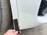 someone is holding a remote control in front of a white car