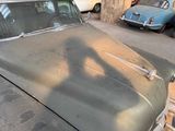 an old car parked in a parking lot next to other cars