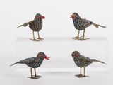 three small metal birds sitting on top of a clear shelf