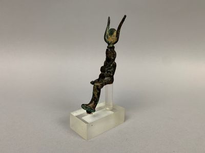 statue en bronze représentant un homme tenant un oiseau, posée sur un socle transparent