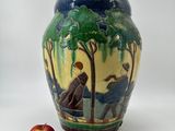 un vase orné d'une peinture, avec une pomme à côté