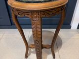 une vieille table en bois avec un plateau en marbre, posée sur un sol carrelé