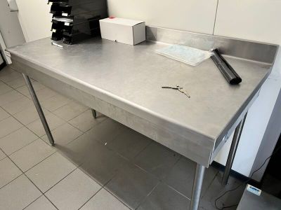 une grande table en inox dans une cuisine où il y a beaucoup de désordre