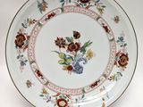 a plate with a floral design on it on a stand