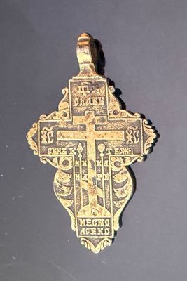 a gold cross on a black surface with a black background