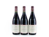 trois bouteilles de vin rouge posées l'une à côté de l'autre sur une surface blanche
