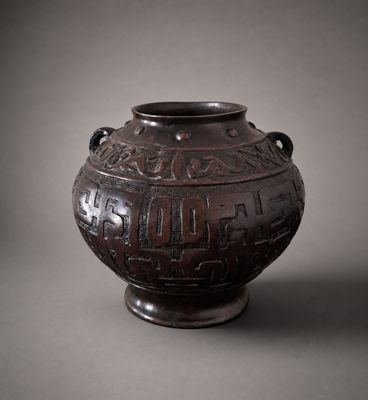 un vieux vase marron, orné d'une inscription, posé sur une table