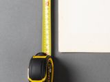 a measuring tape on the table next to a piece of paper