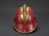 an old red helmet with gold accents on a black background