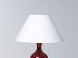 une lampe de table rouge surmontée d'un abat-jour blanc