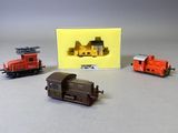 trois trains miniatures assis l'un à côté de l'autre sur une table