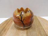 a vase with a tree on it sitting on a wooden table
