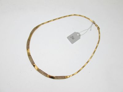 un collier en or posé sur une surface blanche, avec une étiquette de prix