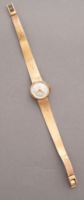 un gros plan d'une montre-bracelet dorée posée sur une surface grise