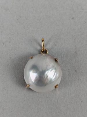a close up of a white pearl pendant on a white surface