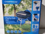 La boîte d'un barbecue Campingaz Party est ouverte sur la table.