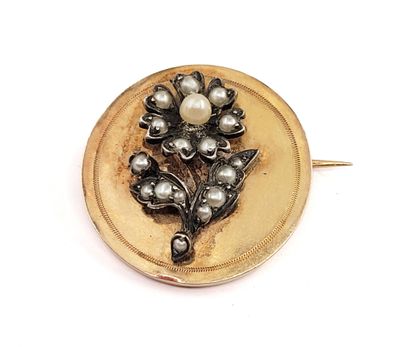 a gold brooch with pearls on it on a white surface