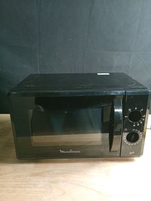 un petit micro-ondes noir posé sur une table en bois