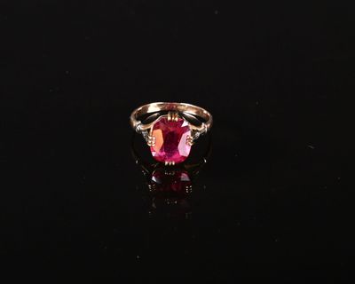 une bague en tourmaline rose et diamants posée sur un fond noir