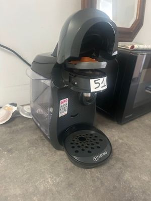 a coffee maker sitting on the floor next to a microwave