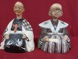 paire de figurines asiatiques posées sur un tissu rouge, sur fond rouge