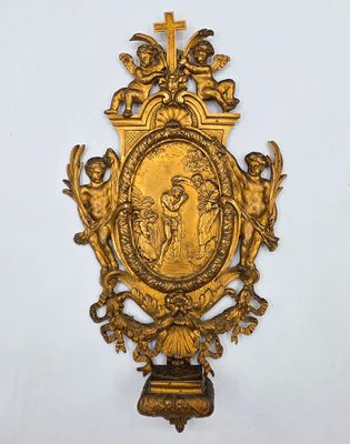 une plaque en or richement décorée, représentant des anges et une croix, accrochée au mur