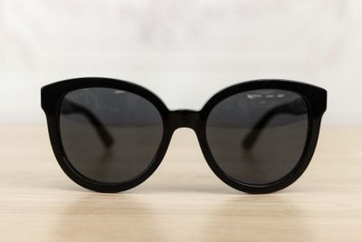 black cat eye sunglasses on a wooden table with a white background