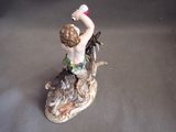 a figurine of a boy with a bottle of wine sitting on a dog