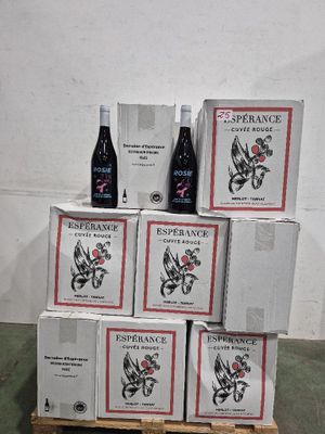 Plusieurs cartons de vin sont empilés sur une palette dans un entrepôt