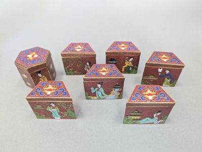 six petites boîtes ornées de personnages asiatiques, posées sur une surface blanche