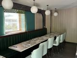 tables and chairs in a restaurant with green walls and a large window