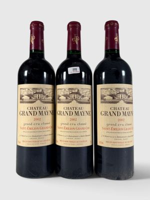 trois bouteilles de vin rouge posées l'une à côté de l'autre sur une surface blanche