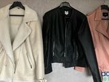 three leather jackets hanging on a wall with clothes on a hanger