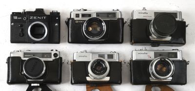 plusieurs vieux appareils photo sont alignés sur une surface blanche