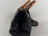 a black purse with bamboo handles and a chain hanging from the handle