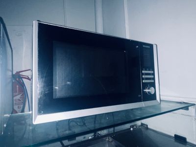 un micro-ondes posé sur une étagère en verre