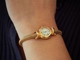 a woman that is wearing a gold watch on her wrist