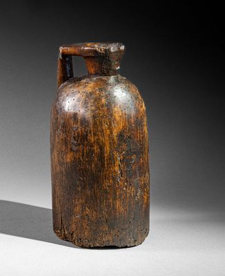 an old wooden bottle with a handle sitting on a white surface