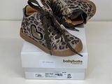 des chaussures de bébé à imprimé léopard posées sur une boîte, sur une surface blanche