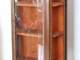 a wooden cabinet with a glass door in the corner of the room