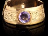 une photo d'un bracelet en or orné d'une pierre violette au centre