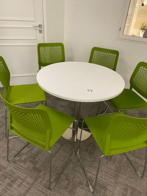 a white table with four green chairs around it