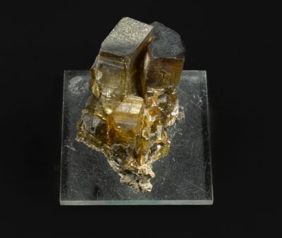 un morceau d'or posé sur un bloc de verre à fond noir