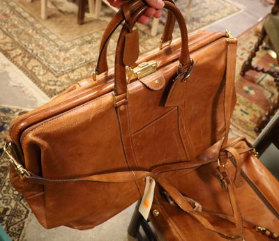 a person holding a brown leather bag in their hand
