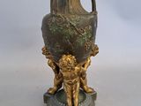un vase en bronze orné d'un lion, posé sur un socle