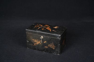 une vieille boîte noire et dorée posée sur une table noire