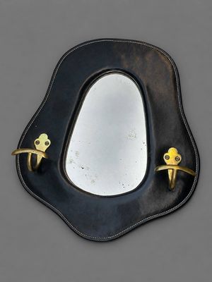 une image représentant un miroir muni d'une poignée dorée accroché à un mur gris