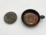 a coin next to a small cup on a white surface