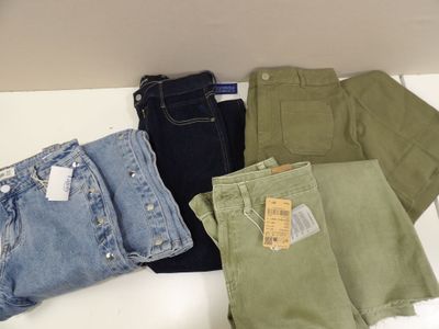 Plusieurs paires de jeans sont disposées sur une surface blanche