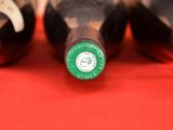 four bottles of wine are lined up on a red surface